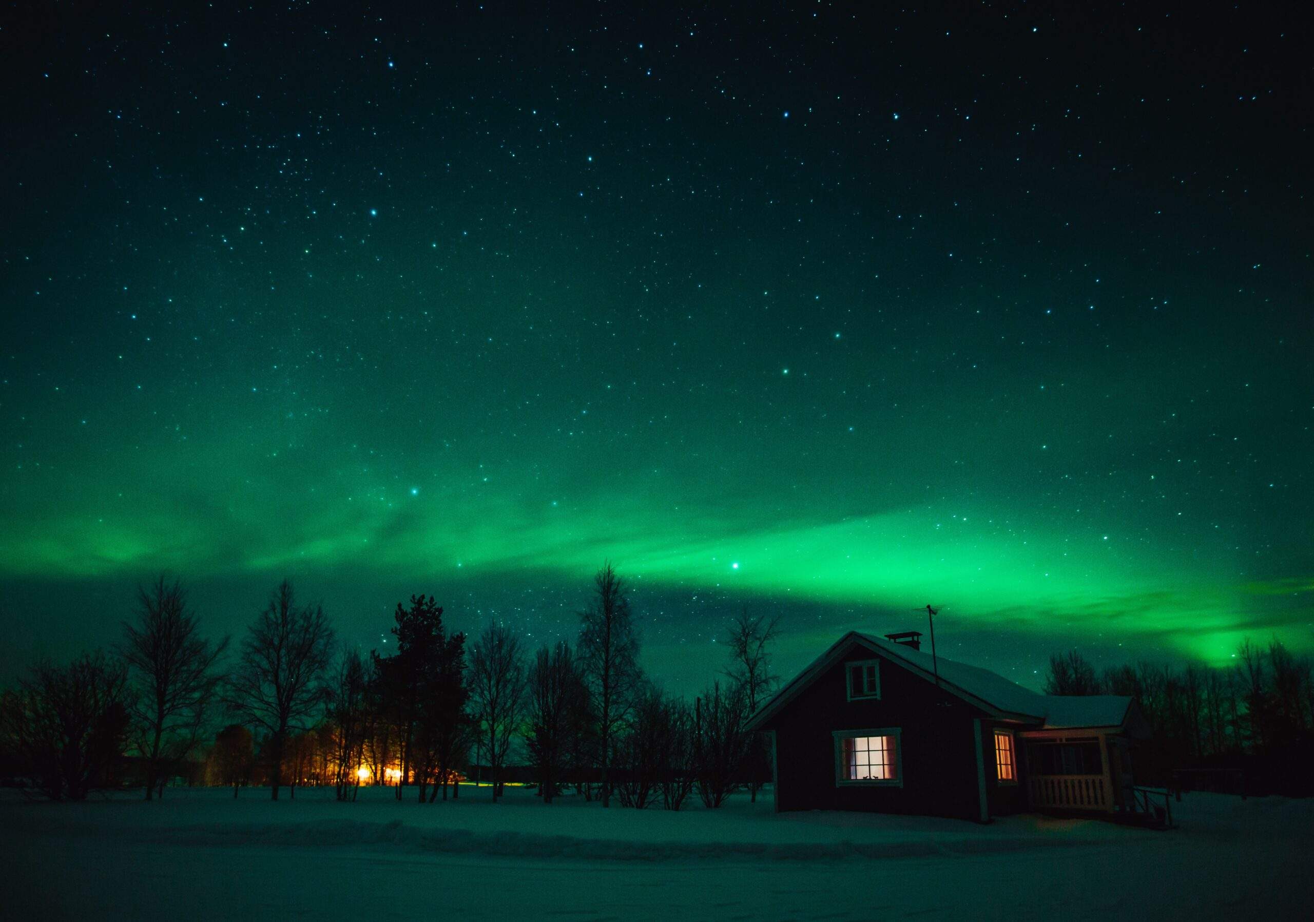 Northern lights (Aurora Borealis) over  cottage in Lapland village. Finland