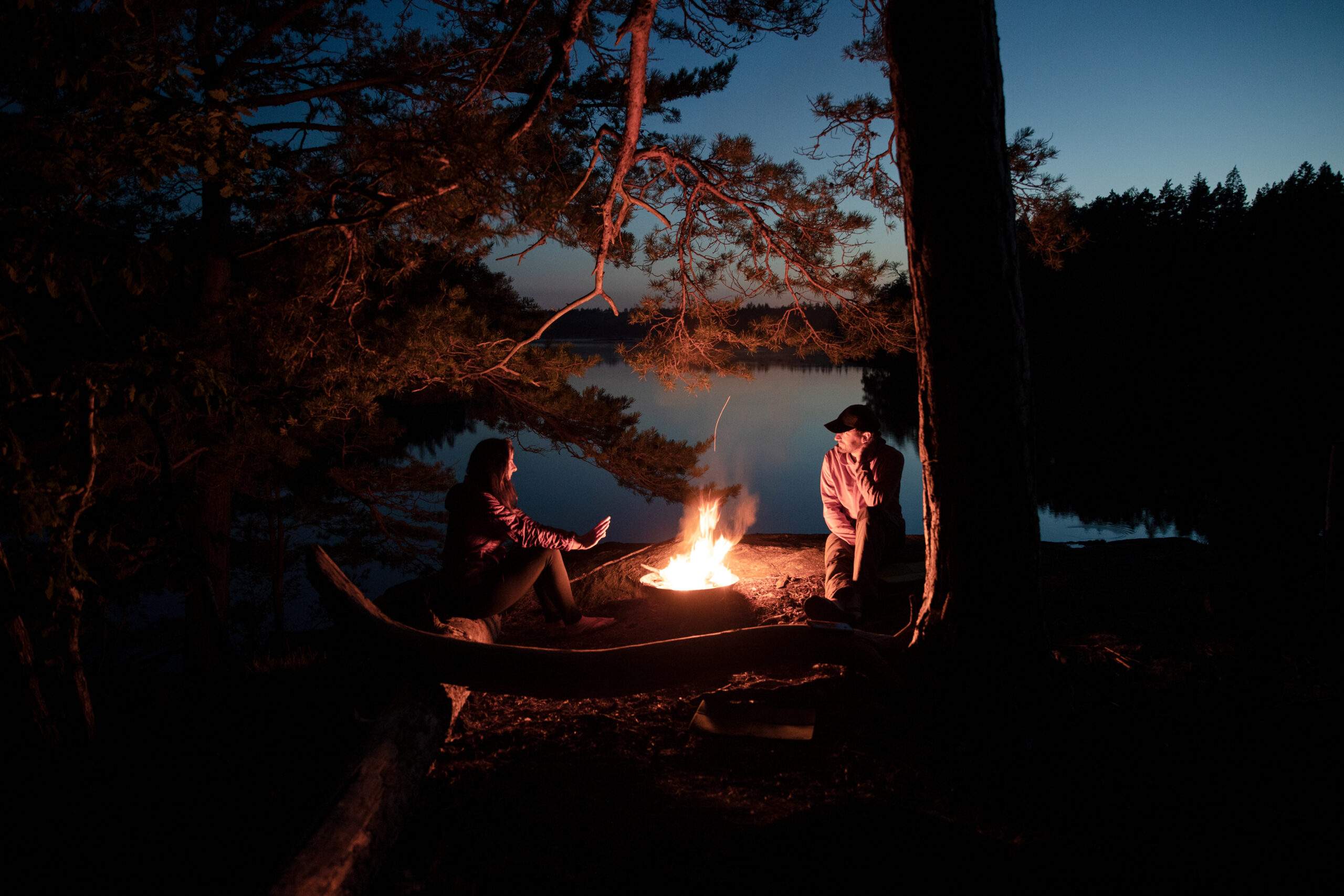 couple profitant de la chaleur d'un feu de camp au bord du lac